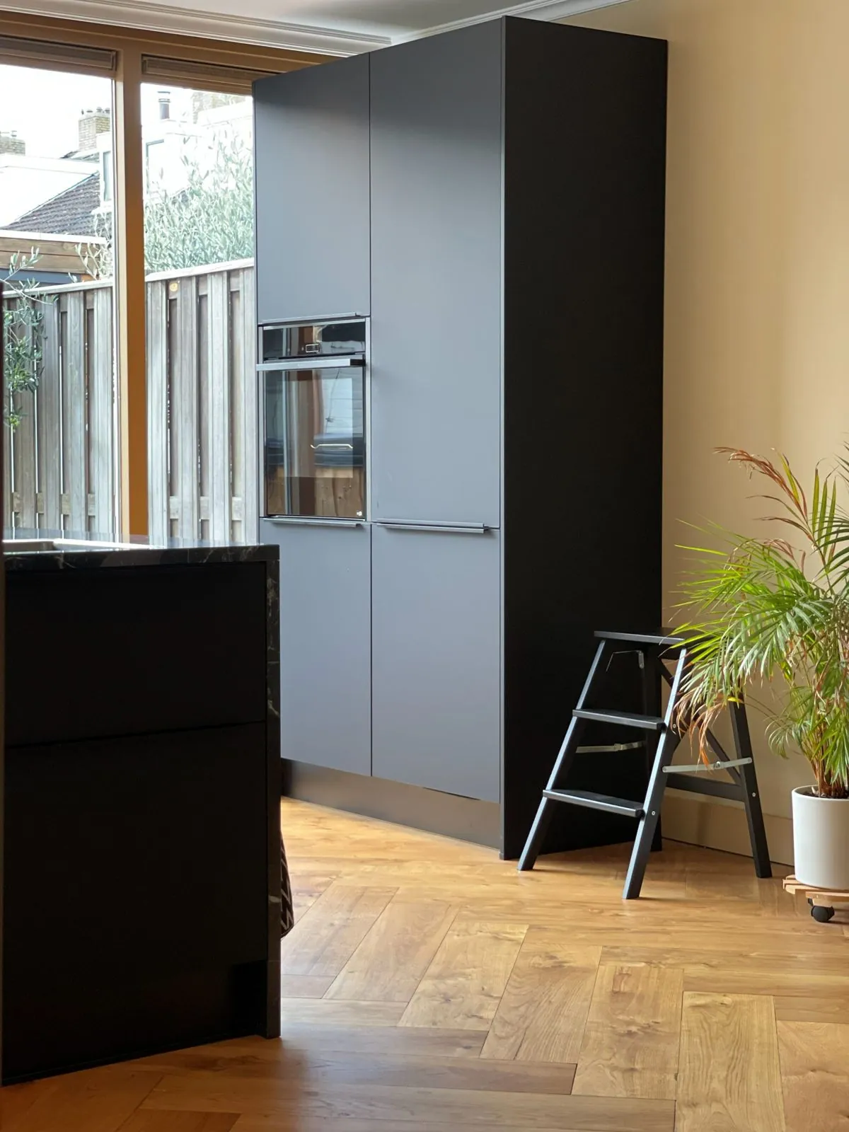 Cabinet wall in matt black on the existing oak herringbone floor